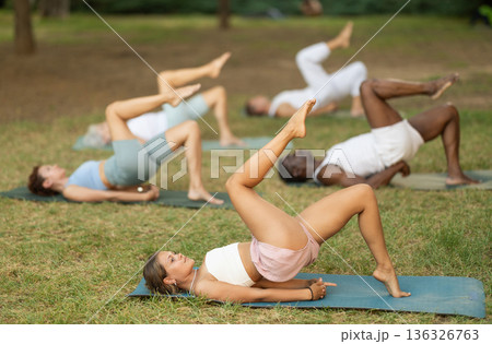 Women and men of multinational in casual sportswear doing yoga outdoors performing Purvottanasana 136326763