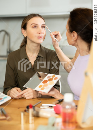 Adult woman doing makeup to young woman Adult woman doing makeup to young woman 136326856
