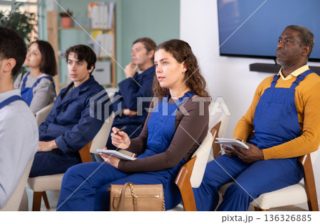 During lecture meeting, girl worker listen to teacher and write down summary 136326885