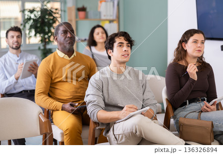 Young man listens and takes notes in lecture hall 136326894
