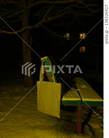 tote bag hanging on the back of a snowy bench at night in the park tote bag hanging on the back of a snowy bench at night in the park 136326917