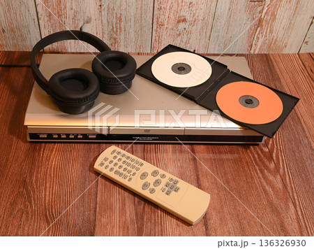 silver dvd player with headphones remote controls and compact discs on the table silver dvd player with headphones remote controls and compact discs on the table 136326930