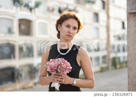 Woman brought flowers to the cemetery and cries over the death of beloved relative Woman brought flowers to the cemetery and cries over the death of beloved relative 136326971