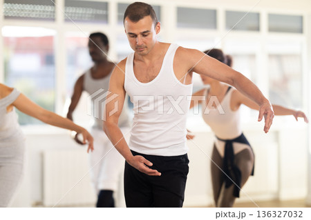 Concentrated women and men rehearsing ballet dance in class Concentrated women and men rehearsing ballet dance in class 136327032