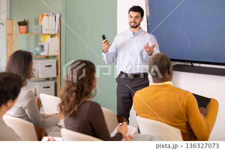 Group of students listening to coach speaking on topic during educational session 136327073