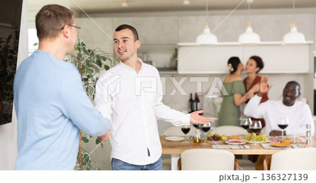 Warm handshake from host to friend at home dinner event Warm handshake from host to friend at home dinner event 136327139