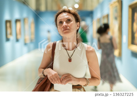 Woman viewing art gallery with brochure Woman viewing art gallery with brochure 136327225