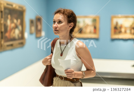 Woman viewing art gallery with brochure 136327284