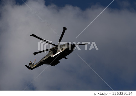 Military Helicopter Silhouette Against Dramatic Cloudy Sky in Flight Military Helicopter Silhouette Against Dramatic Cloudy Sky in Flight 136329114