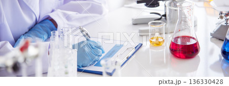 Banner Asian woman scientist hand write note research in medical lab look at science microscope. Panorama biology chemistry lab. Asian Female technician laboratory using microscope with copy space Banner Asian woman scientist hand write note research in medical lab look at science microscope. Panorama biology chemistry lab. Asian Female technician laboratory using microscope with copy space 136330428