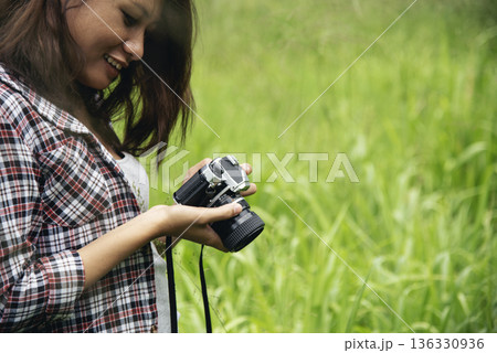Close up hands Asian Women look at dslr digital camera vintage film style take a photo. Professional female photographer look at picture outdoor. Young woman hands shooting photo in green nature park Close up hands Asian Women look at dslr digital camera vintage film style take a photo. Professional female photographer look at picture outdoor. Young woman hands shooting photo in green nature park 136330936