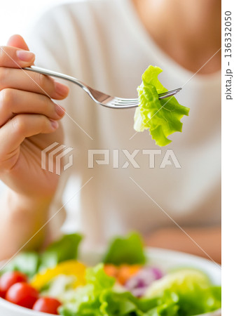 フォークでサラダを口に運ぶ手元のクローズアップ 136332050