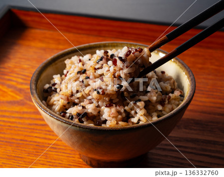 木製トレーに置かれた茶碗に入った雑穀米を箸で持ち上げる様子 木製トレーに置かれた茶碗に入った雑穀米を箸で持ち上げる様子 136332760
