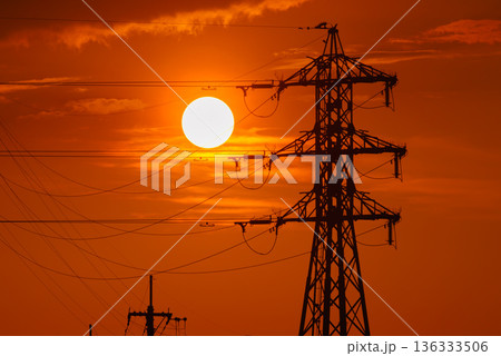 夕焼けの太陽と送電線のシルエット　電力インフラと都市風景 136333506