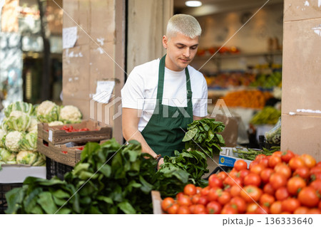 Guy shop seller puts spinach goods on display case Guy shop seller puts spinach goods on display case 136333640