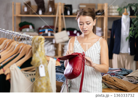 Near rack, girl buys lady handbag, chooses items Near rack, girl buys lady handbag, chooses items 136333732