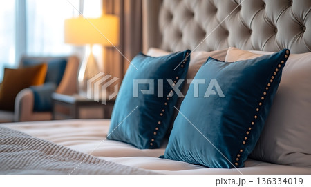 The bed is made with two blue pillows and a white pillow The bed is made with two blue pillows and a white pillow 136334019