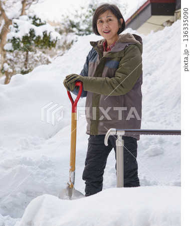 大雪の中でスコップを持って途方に暮れる女性 大雪の中でスコップを持って途方に暮れる女性 136335090
