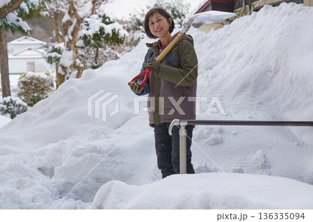 大雪の中でスコップを持って途方に暮れる女性 大雪の中でスコップを持って途方に暮れる女性 136335094