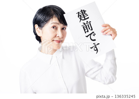 建前ですと書かれた紙を片手で持ちドヤ顔のシニア女性 建前ですと書かれた紙を片手で持ちドヤ顔のシニア女性 136335245