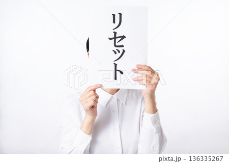 リセットと書かれた紙を持つ白いシャツを着た人物 136335267