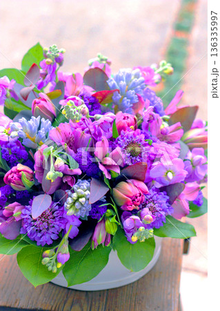 チューリップなど春の花を使った淡い色のフラワーアレンジメント 136335997