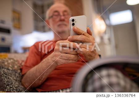 Elderly man holding and using a smartphone. Elderly man holding and using a smartphone. 136336764