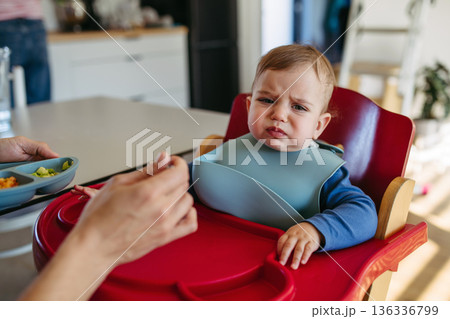 Toddler crying while father feeding him. 136336799