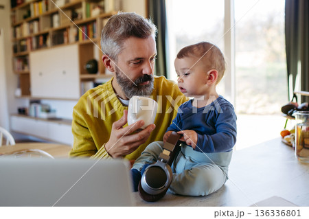 Dad working from homeoffice and taking care of toddler. 136336801