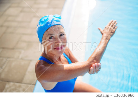 High angle view of older swimmer sitting on poolside. 136336960