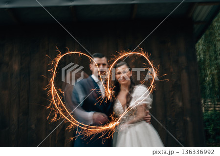 Bride and groom with sparklers creating a heart shape. 136336992