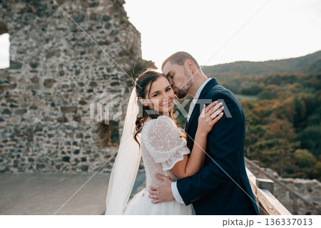 Bride and groom dancing, looking at each other. Wedding couple standing outside near ruins. 136337013