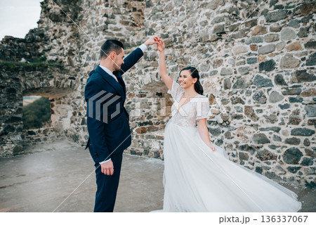 Bride and groom dancing, looking at each other. Wedding couple standing outside near ruins. Bride and groom dancing, looking at each other. Wedding couple standing outside near ruins. 136337067