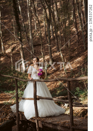 Bride in a snow-white wedding dress in nature, surrounded by a forest. 136337162