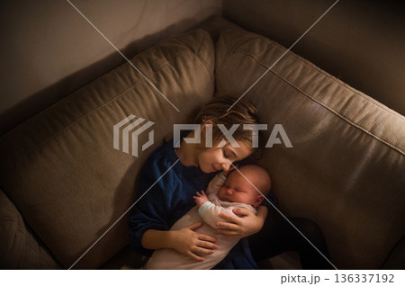 Young girl holding newborn sister. Tender sibling moment. Young girl holding newborn sister. Tender sibling moment. 136337192