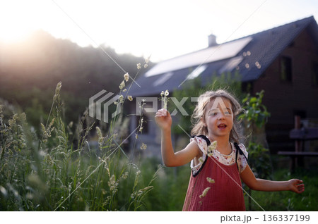 Girl in front of house with solar panels on roof. Girl in front of house with solar panels on roof. 136337199
