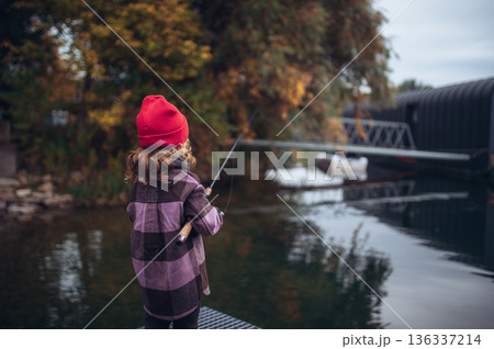 Child enjoying fishing outdoors during cold season. Child enjoying fishing outdoors during cold season. 136337214