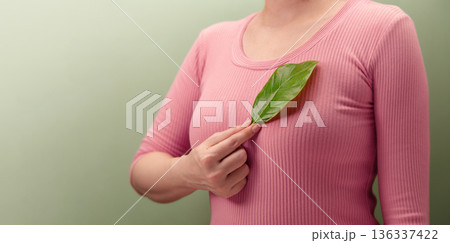 Woman holding green leaf over her Chest, Heart. Environmental awareness Woman holding green leaf over her Chest, Heart. Environmental awareness 136337422