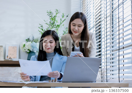 Team of partners Asian business woman discussing project on laptop sitting at table in office. Team of partners Asian business woman discussing project on laptop sitting at table in office. 136337500