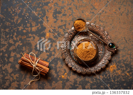 Ground Spice On Decorative Plate With Cinnamon Sticks Beside It 136337832