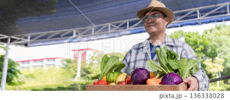 Farmer holding wooden box full of fresh vegetables.  136338028