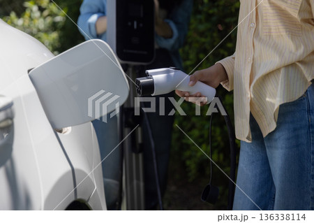 Tennage Girls EV charging an electric car. Power supply for electric car charging. 136338114