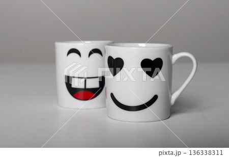 Two white ceramic mugs with playful emoji faces. Cute smiling happy and valentine love cup designs, Two white ceramic mugs with playful emoji faces. Cute smiling happy and valentine love cup designs, 136338311