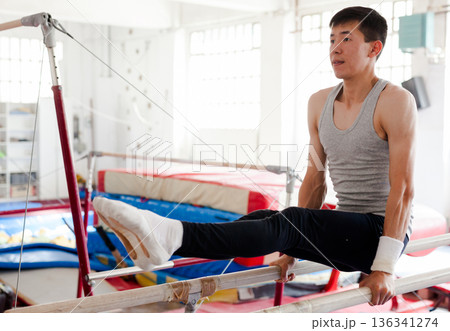 Male athlete doing complicated exciting trick on pommel horse in professional gym Male athlete doing complicated exciting trick on pommel horse in professional gym 136341274