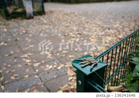 House keys resting on a garden fence in autumn. Everyday outdoor scene showing a personal item, representing routine, mobility, and seasonal life. House keys resting on a garden fence in autumn. Everyday outdoor scene showing a personal item, representing routine, mobility, and seasonal life. 136341646