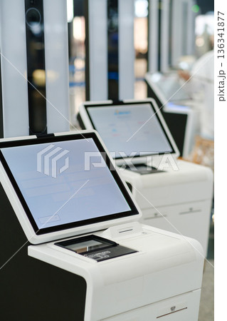Modern check-in kiosks occupy a prominent area in a busy airport terminal, streamlining the travel process for passengers efficiently during morning hours Modern check-in kiosks occupy a prominent area in a busy airport terminal, streamlining the travel process for passengers efficiently during morning hours 136341877