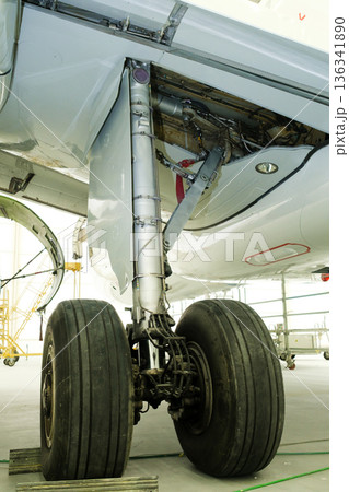 Landing gear maintenance and inspection of an aircraft located in a hangar with tools and equipment visible nearby during daylight hours 136341890