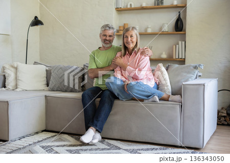 Adult couple sitting and embracing on sofa feeling coziness calm and tenderness 136343050