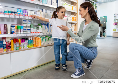 Woman supporting young girl choosing item in pharmacy 136343073