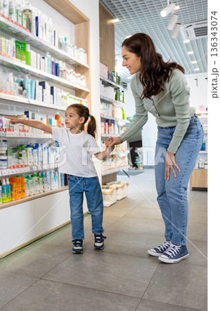 Joyful mother and daughter browsing products in pharmacy 136343074